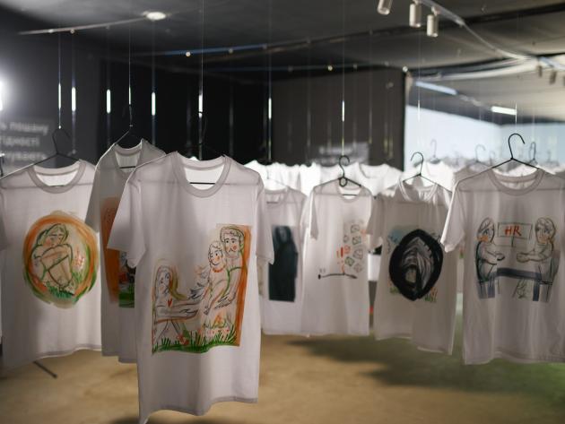 Installation.Recognize.React (c) Christof Ott/Pfarrei Koblenz St. Aposteln TShirts mit Kursskizzen über Missbrauchserfahrungen gestaltet hängen auf Kleiderbügeln in einem Raum
