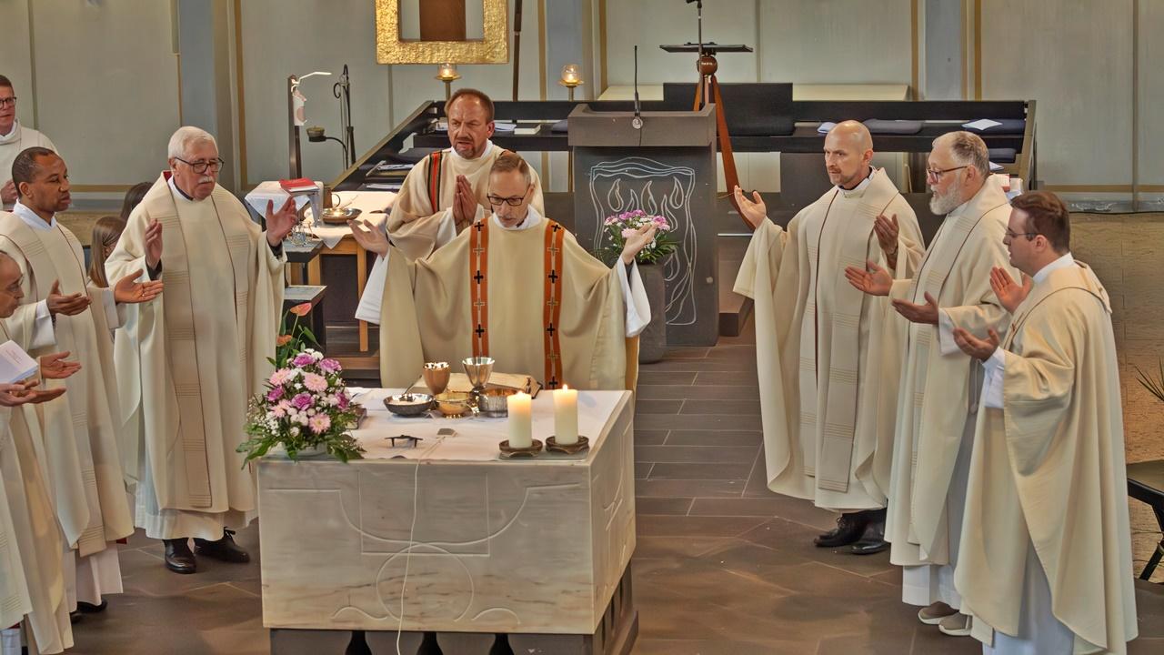 zentral ist der Altar der Kirche St. Franziskus, Koblenz zu sehen, dahinter Priester Heinz-Peter Wilbertz und weitere Pastöre, die im Halbreis um ihn stehen