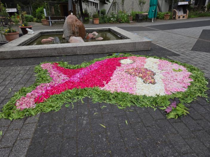 Ein Fisch als Blumenteppich. Kontur grün, Kopf und Körper in den Farben rosa und weiß übergehend zum Schwanz pink und rosa
