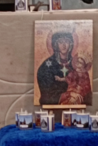 Vor dem Altar in St. Franziskus steht ein Tisch bedeckt mit blauem Tuch darauf ein Bild der Muttergottes und Kerzen. Davor eine Vase mit eine roten Rose und weitere Kerzen