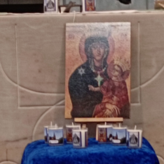 Vor dem Altar in St. Franziskus steht ein Tisch bedeckt mit blauem Tuch darauf ein Bild der Muttergottes und Kerzen. Davor eine Vase mit eine roten Rose und weitere Kerzen