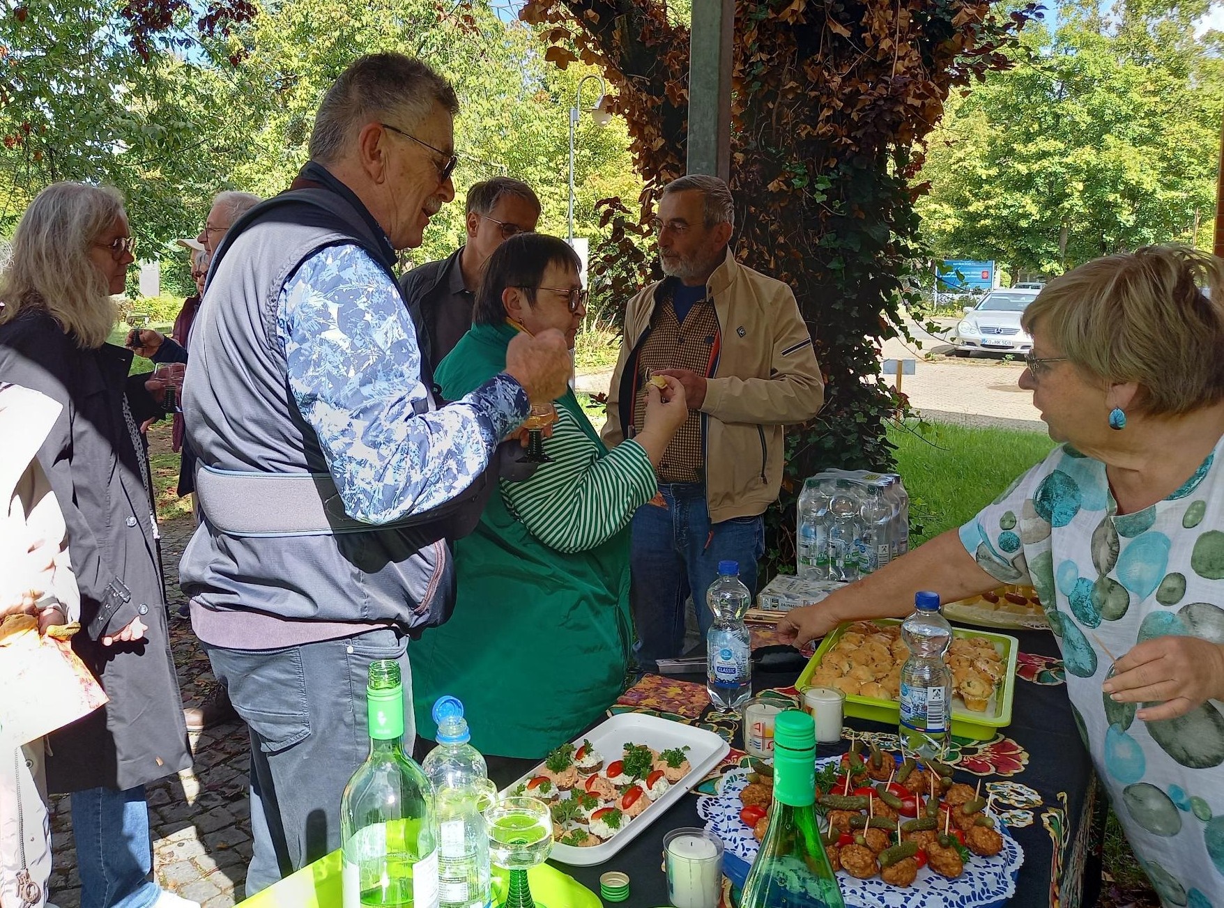 Ein im Freien aufgebautes Buffet mit schön angerichteten Häppchen, davor stehen Personen