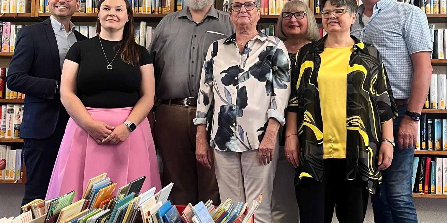 Feierlich gekleidete Personen vor Bücherregalen, davor Kisten mit Büchern (c) KÖB St. Laurentius Koblenz-Moselweiß Feierlich gekleidete Personen vor Bücherregalen, davor Kisten mit Büchern
