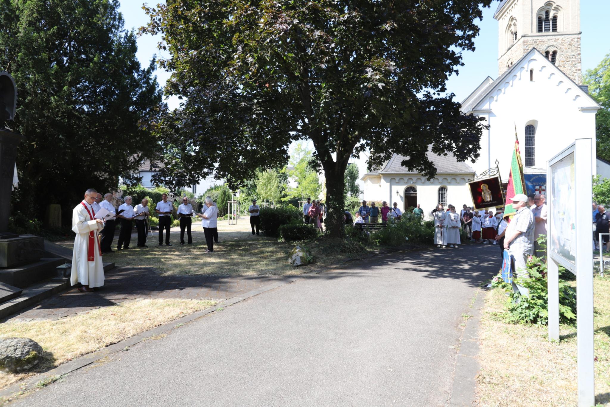 Pastor und Gemeinde stehen um das Ehrenmal für die Kriegsopfer auf dem Friedhof Moselweiß