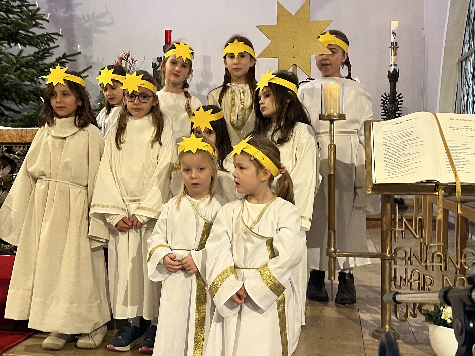 Neun Kinder verschiedenen Alters als Engel gekleidet, mit einem Stirnband mit einem Stern, im Altarraum einer Kirche