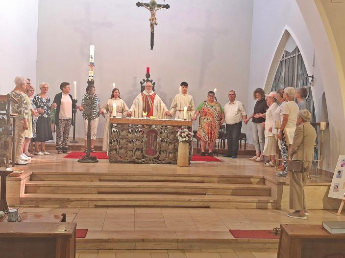 zu sehen ist der Altarraum der Kirche St. Beatus, hinter dem Altar steht Pfarrer Michael Frevel, rechts und links von ihm stehen Personen im Halbkreis, alle haben sich an der Hand gefasst