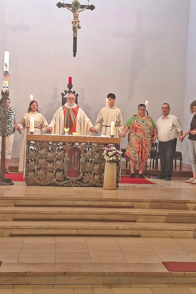 zu sehen ist der Altarraum der Kirche St. Beatus, hinter dem Altar steht Pfarrer Michael Frevel, rechts und links von ihm stehen Personen im Halbkreis, alle haben sich an der Hand gefasst