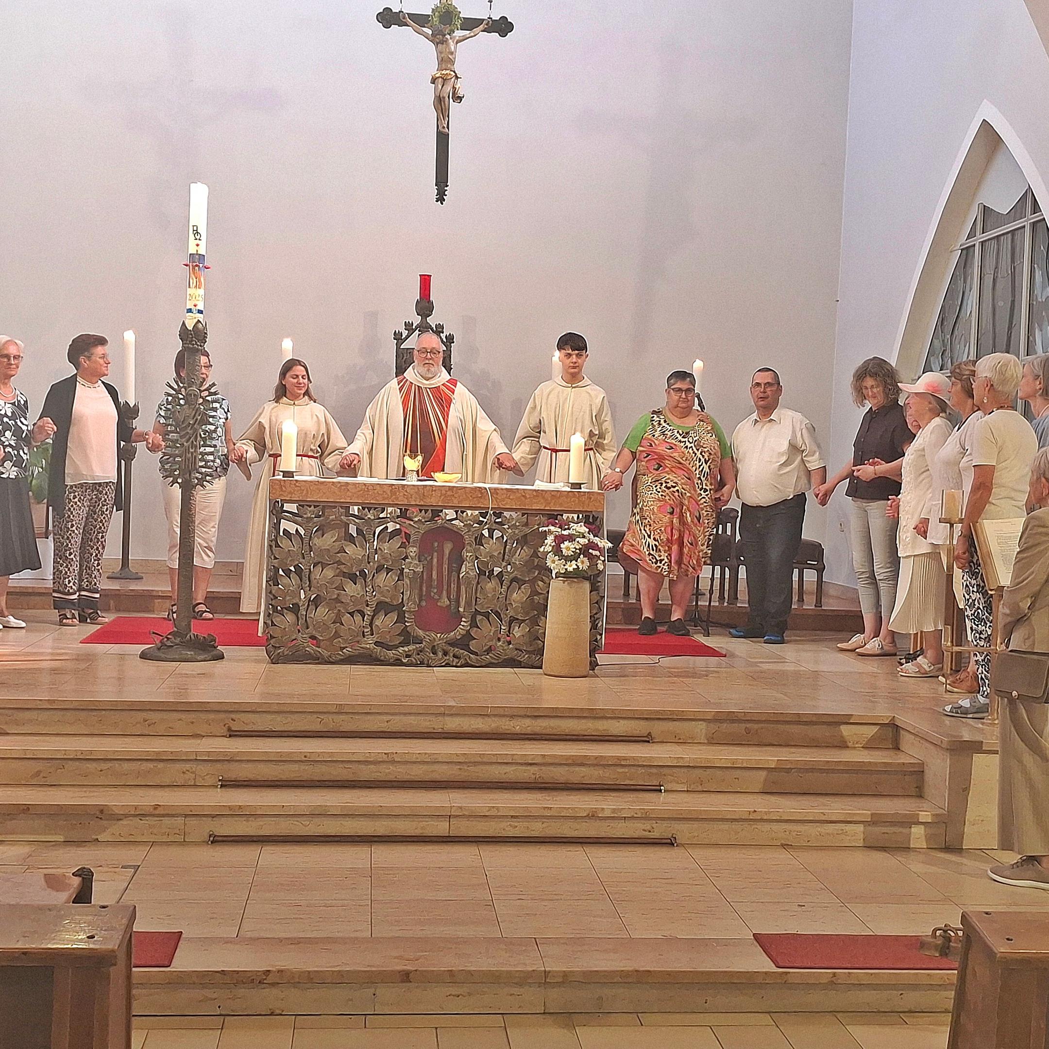zu sehen ist der Altarraum der Kirche St. Beatus, hinter dem Altar steht Pfarrer Michael Frevel, rechts und links von ihm stehen Personen im Halbkreis, alle haben sich an der Hand gefasst