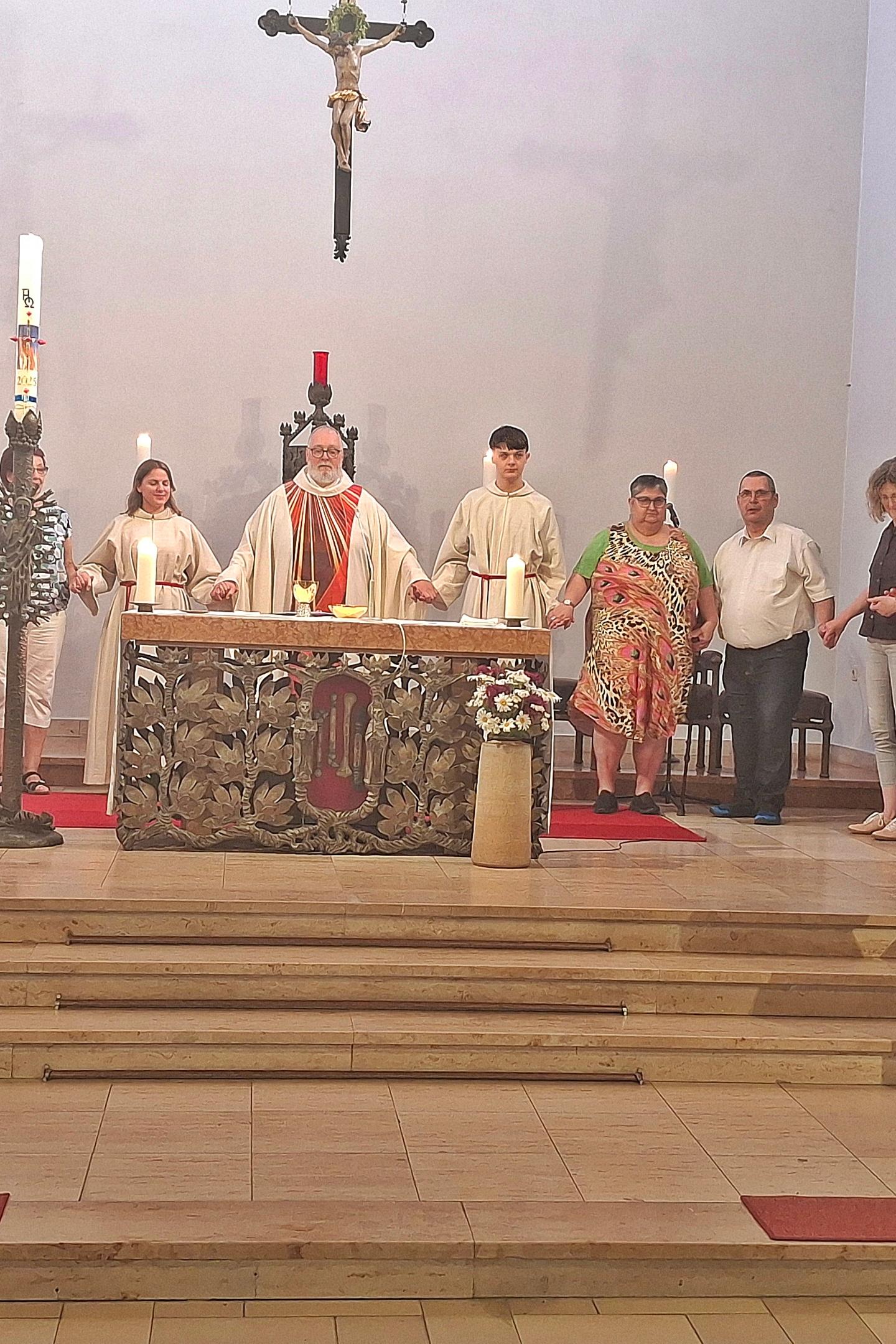zu sehen ist der Altarraum der Kirche St. Beatus, hinter dem Altar steht Pfarrer Michael Frevel, rechts und links von ihm stehen Personen im Halbkreis, alle haben sich an der Hand gefasst