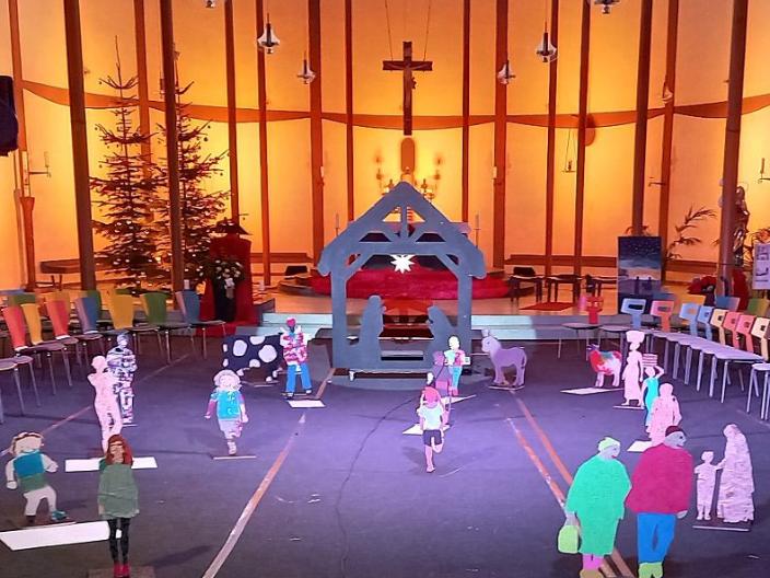 Vor dem in sanftem Licht beleuchteten Altarraum der St. Elisabethkirche steht eine außergewöhnliche Krippe. Wie ein Schwippbogen lebensgroß ist der Stall gestaltet  mit Maria und Josef zwischen ihnen ein Stern. Holzfiguren aus Brettern gesägt - als Menschen, die uns tagtäglich auf der Straße begegnen,  aber auch Ochs, Esel und Schaf kommen von der Krippe auf uns zu. Es entsteht das Gefühl auf einem Marktplatz oder auf einem Feld zu sein, denn dieses Krippe nimmt einen großen Raum ein.