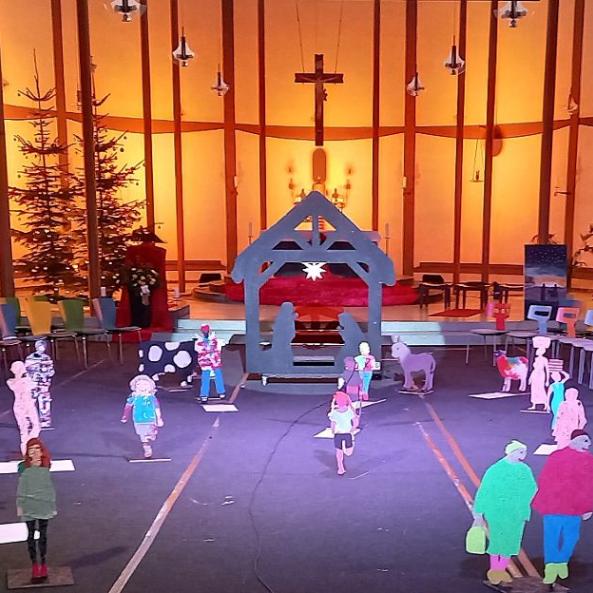 Vor dem in sanftem Licht beleuchteten Altarraum der St. Elisabethkirche steht eine außergewöhnliche Krippe. Wie ein Schwippbogen lebensgroß ist der Stall gestaltet  mit Maria und Josef zwischen ihnen ein Stern. Holzfiguren aus Brettern gesägt - als Menschen, die uns tagtäglich auf der Straße begegnen,  aber auch Ochs, Esel und Schaf kommen von der Krippe auf uns zu. Es entsteht das Gefühl auf einem Marktplatz oder auf einem Feld zu sein, denn dieses Krippe nimmt einen großen Raum ein.