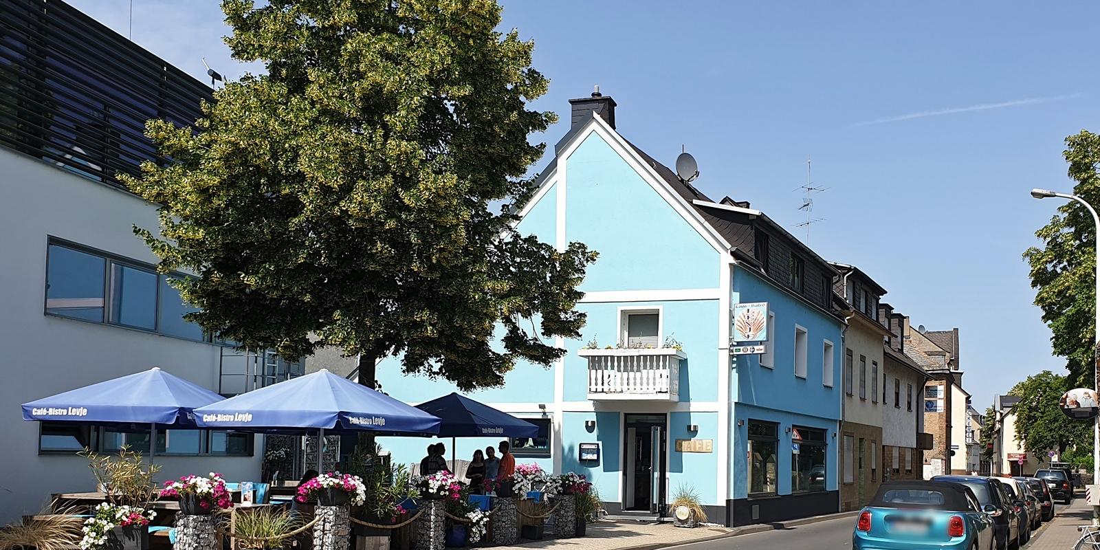 Außengastronomie an einer Straße mit Baum und Sonnenschirmen