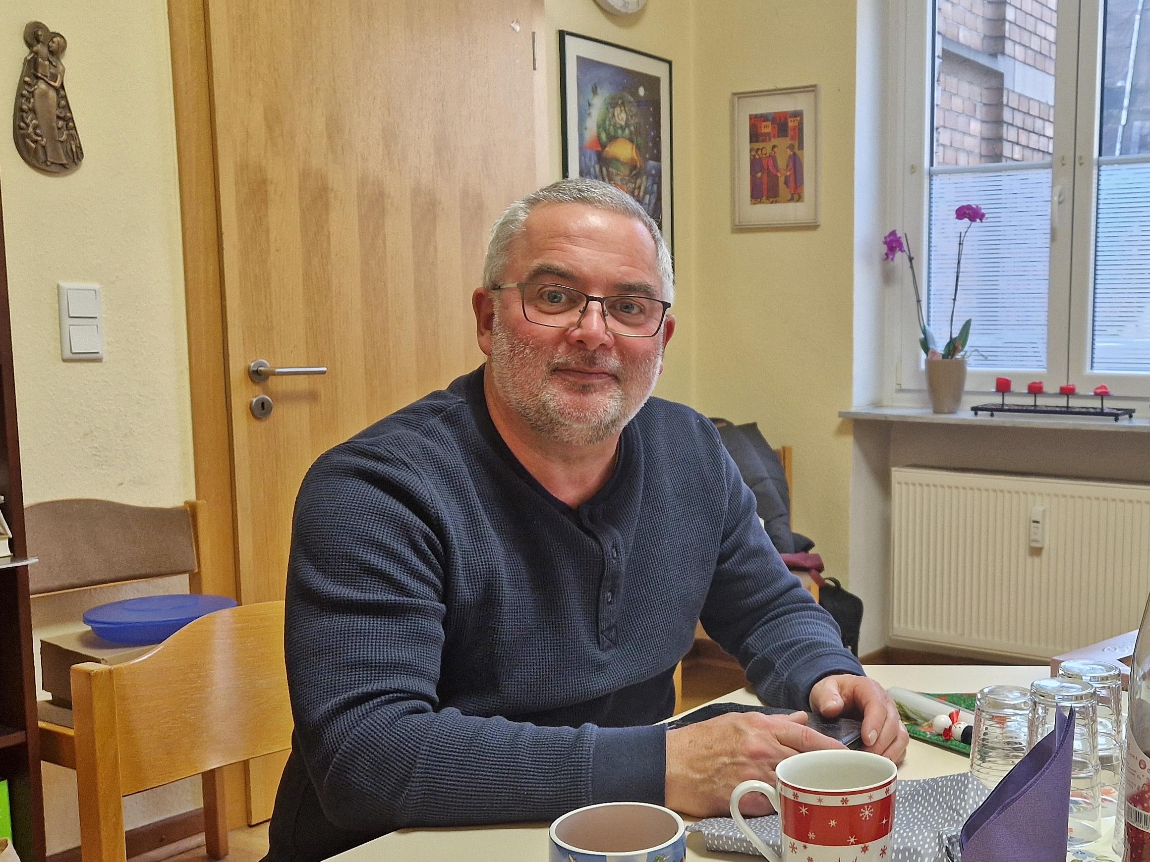 Roman Kalter im Büro Moselweiß, er sitzt an einem Tisch, hat einen blauen Pullover an