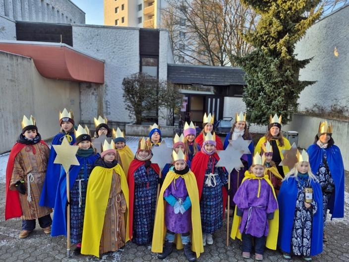 Eine Gruppe Kinder als Sternsinger gekleidet vor der St. Hedwig Kirche, Karthause. Im Hintergrund blauer Himmel
