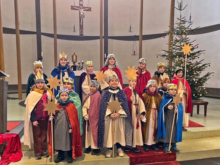 Eine Gruppe Sternsinger steht im Altarraum einer Kirche