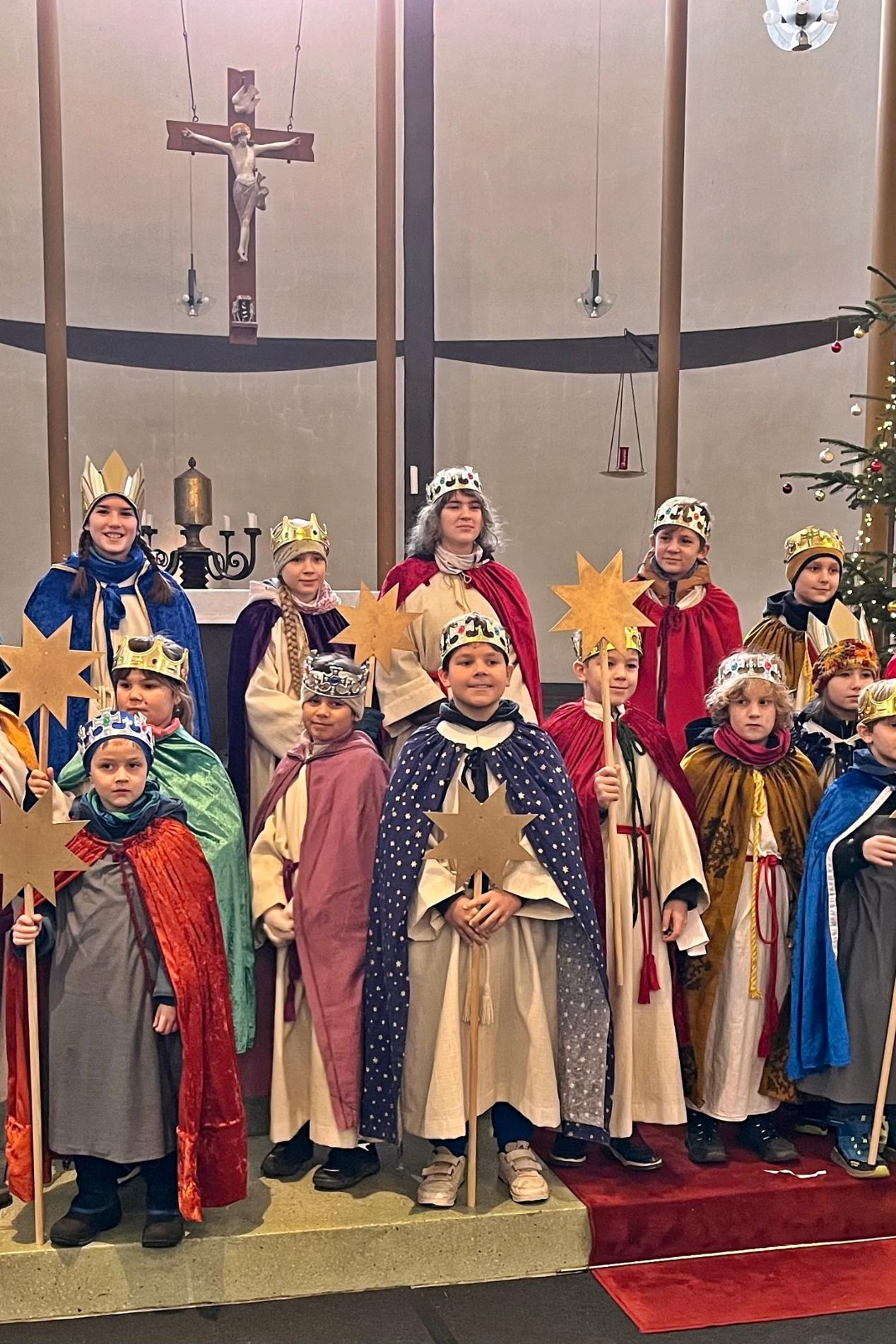 Eine Gruppe Sternsinger steht im Altarraum einer Kirche