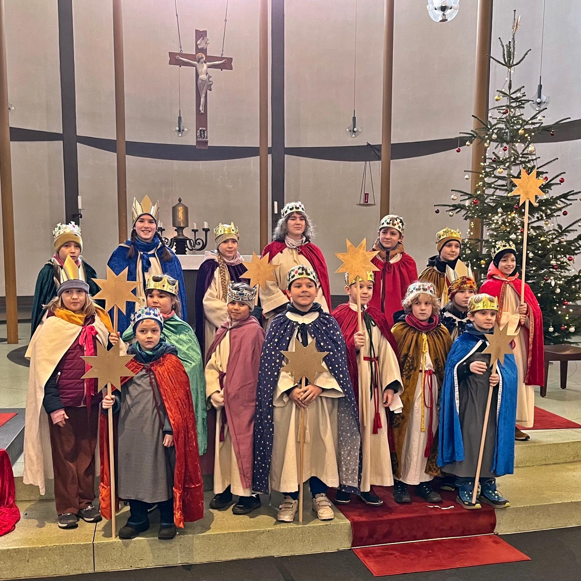 Eine Gruppe Sternsinger steht im Altarraum einer Kirche