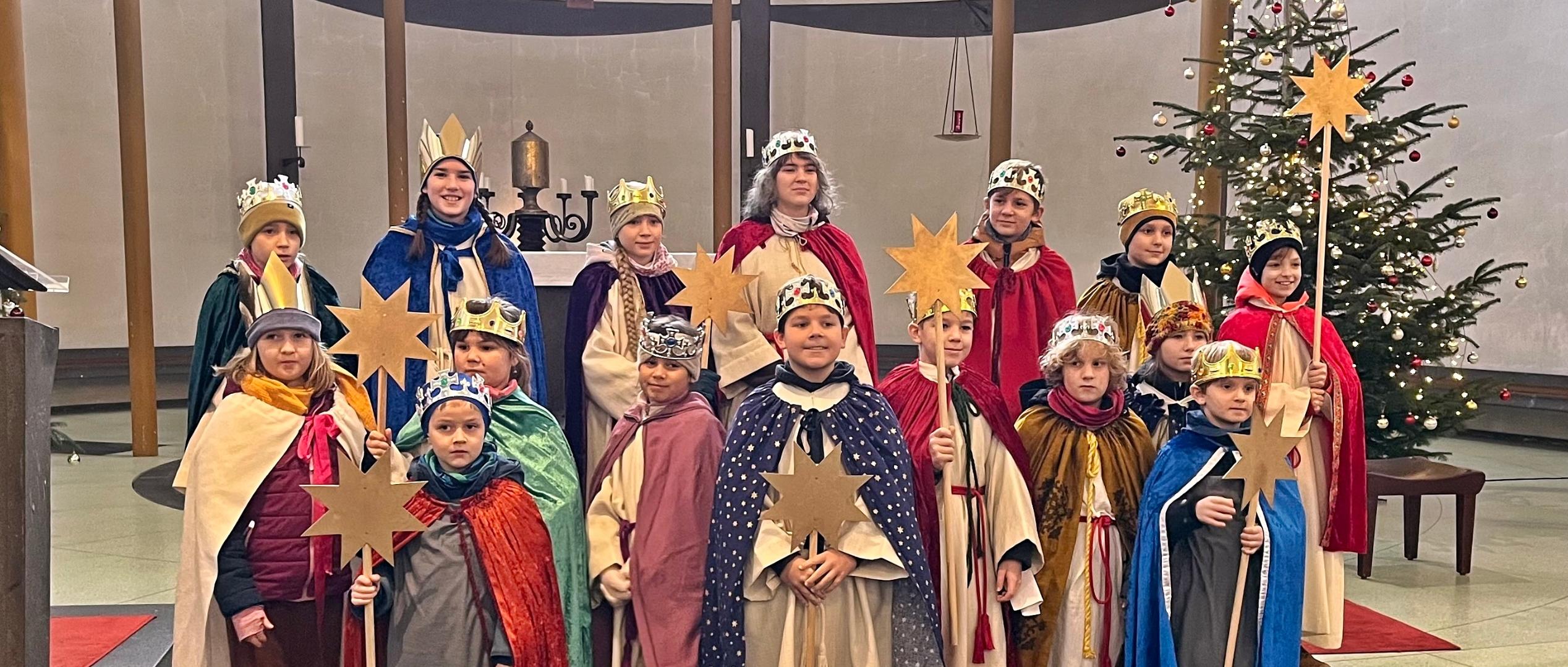 Eine Gruppe Sternsinger steht im Altarraum einer Kirche