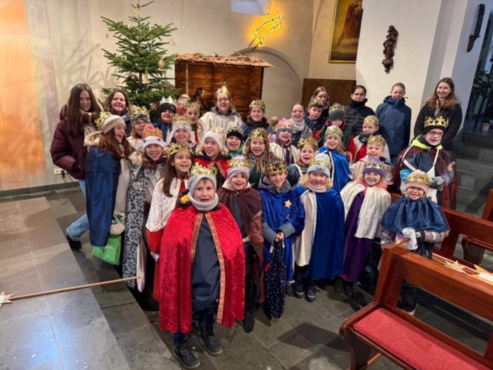Eine fröhliche Sternsingergruppe mit ihren Betreuern,  vor der Krippe der St. Martinus Kirche in Lay