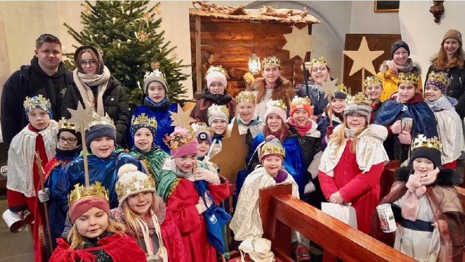 Eine Gruppe Kinder als Sternsinger gekleidet in einer Kirche