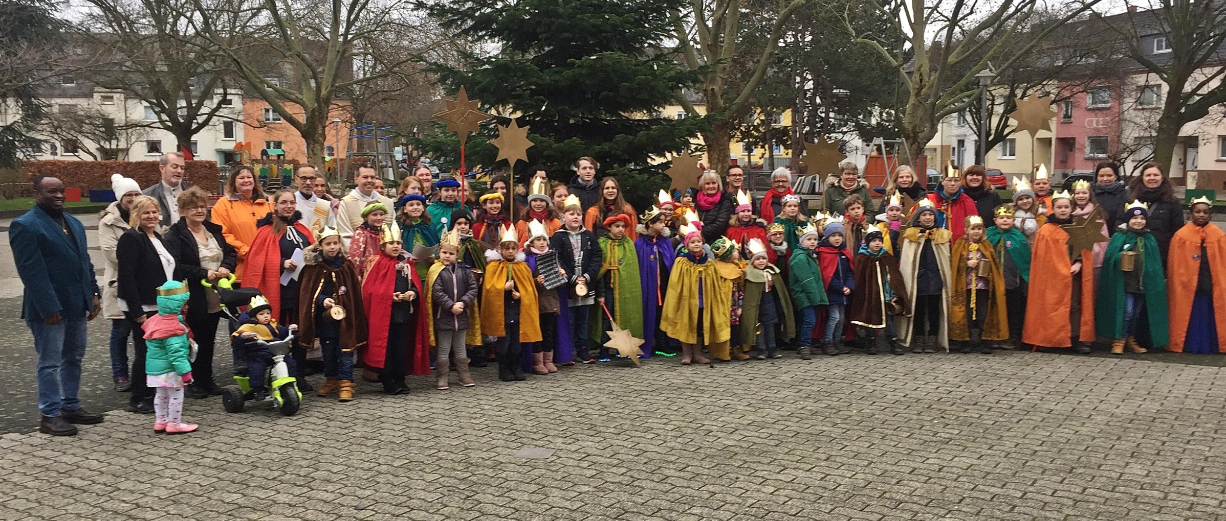 Eine große Gruppe Kinder als Sternsinger verkleidet daneben einige Erwachsene