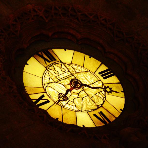 Gelb leuchtende Uhr mit römischen Zahlen in dunkler Umgebung
