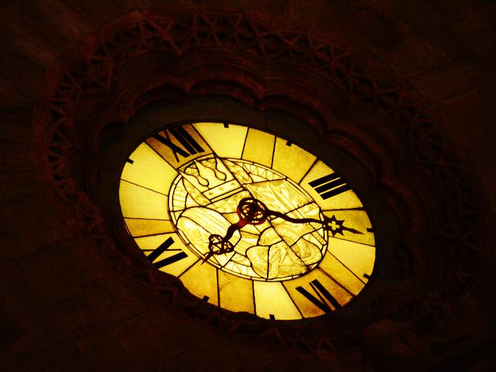 Gelb leuchtende Uhr mit römischen Zahlen in dunkler Umgebung