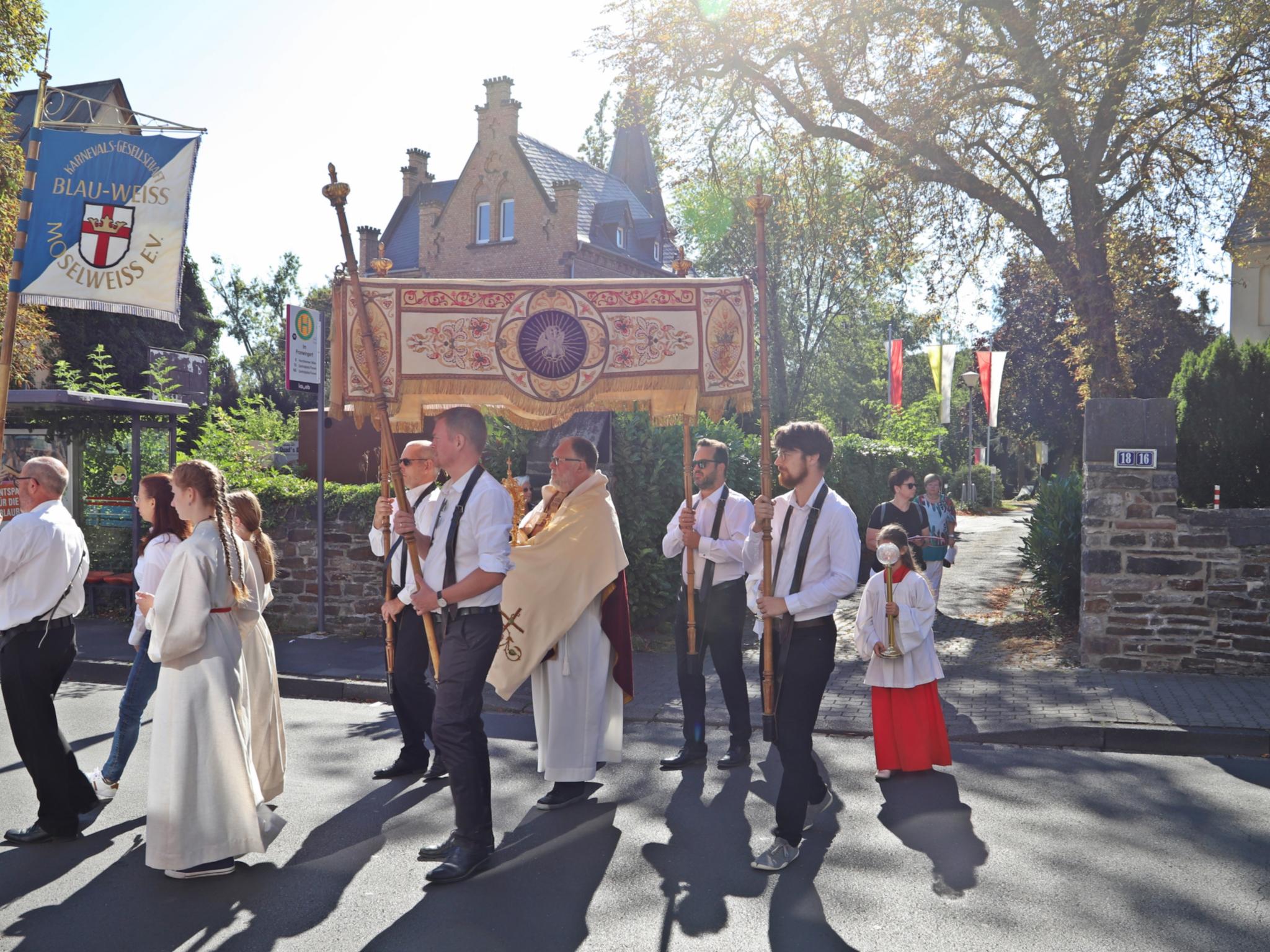 Prozession anlässlich Kirmes St. Laurentius, im Vordergrund der Himmel mit den Trägern, Pfarrer Frevel, Messdienern und Fahnenträger, auf der Koblenzer Straße, im Hintergrund das Kirchengelände mit Fahnen und Pfarrhaus