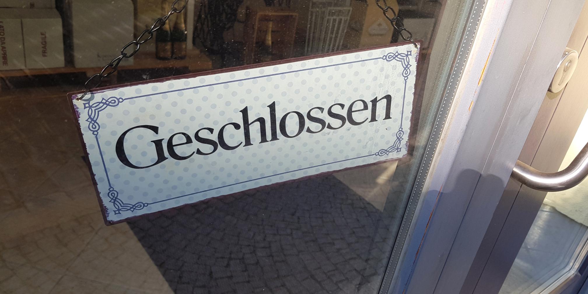 Ein Schild mit dem Schriftzug 'geschlossen' hängt an einer Tür.